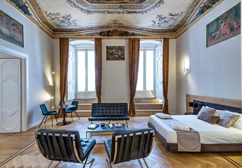 a bedroom with a bed and chairs and a ceiling at Corso Grand suites in Barletta