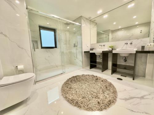 uma casa de banho com um WC, um chuveiro e um tapete. em BelArt Luxury Golf Villa em Aroeira