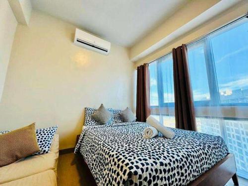 a bedroom with a bed and a window and a couch at Mactan Newtown By The Beach in Lapu Lapu City