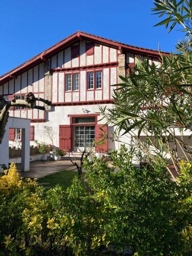 une maison avec un bâtiment rouge et blanc dans l'établissement Location Eyheraldia votre Triplex au cœur du Pays Basque, à Hasparren