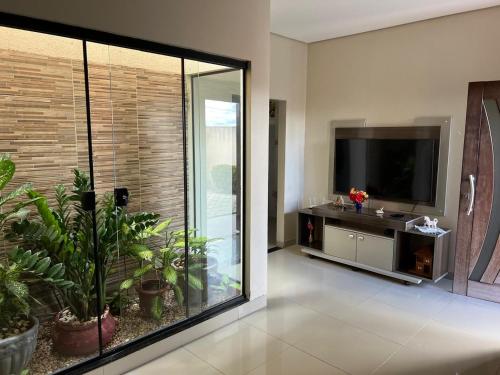 uma sala de estar com uma televisão de ecrã plano e plantas em Casa Mobiliada Itaubas com ar condicionado em Sinop