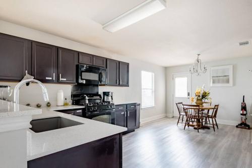 a kitchen with black cabinets and a table with chairs at Serenity Home Near Downtown & Airport in Austin