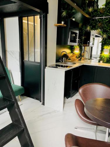 - une cuisine avec des placards noirs, un évier et une table dans l'établissement Studio Mezzanine, à Rouen