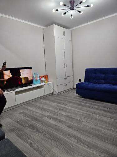 un salon avec un canapé bleu et une télévision dans l'établissement Квартира, à Balkhach