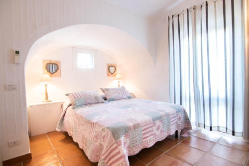 a bedroom with a bed and a large window at BGItalianVacation - Ville Li Conchi in Castiadas