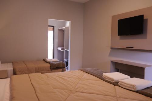 ein Hotelzimmer mit 2 Betten und einem Flachbild-TV in der Unterkunft Pousada Apear in Andradas