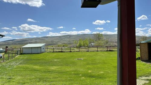 uma vista a partir de uma janela de um campo com uma cerca e montanhas em Infidel Acres Motorcycle Campground em Naches