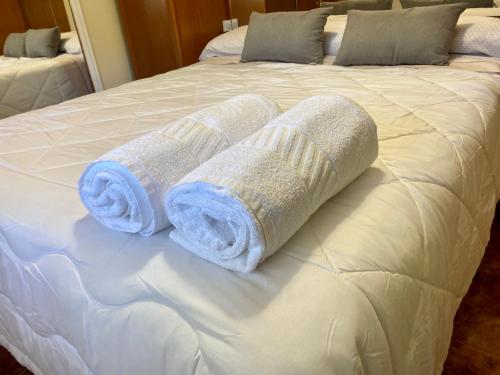 two rolled up towels on a white bed at Chalet con piscina El Refugio de Venecia in El Campillo