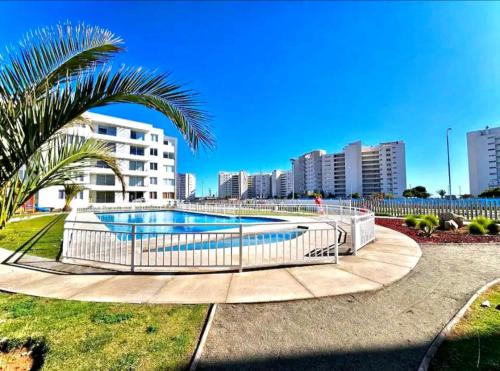 uma piscina num parque com uma palmeira e edifícios em Jardines del Pacífico 3 em La Serena