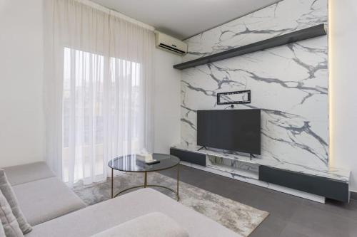 a living room with a tv and a marble wall at Luna 2-BR in Mar Mikhael in Beirut