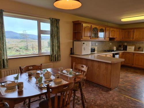a kitchen with a wooden table and a large window at Tigh Mhartin in Glentrasna
