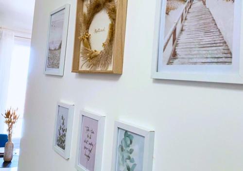 un mur avec des photos encadrées sur un mur blanc dans l'établissement T2 chic & cosy, RER D, Orly 15 min, à Villeneuve-Saint-Georges