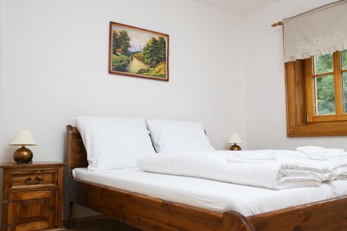 a bed with white sheets and a picture on the wall at Koliba Hubertka in Oravice
