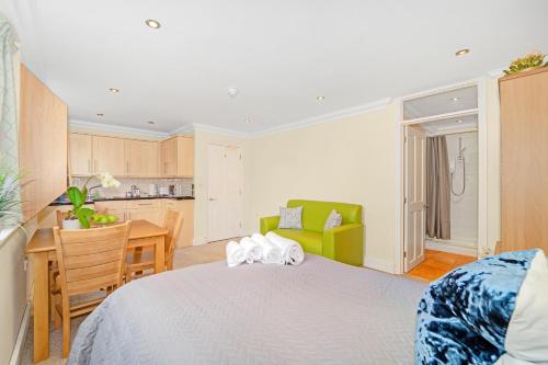 a bedroom with a bed and a desk and a kitchen at Park Views Apartments in Teddington