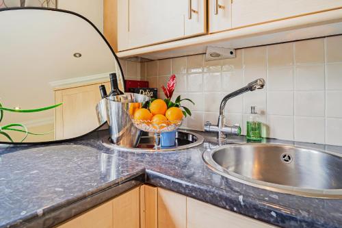 a kitchen counter with a sink and a bowl of oranges at Park Views Apartments in Teddington