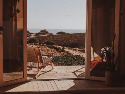 una porta aperta con una sedia che guarda l'oceano di Dreamsea Imsouane Morocco a Imsouane