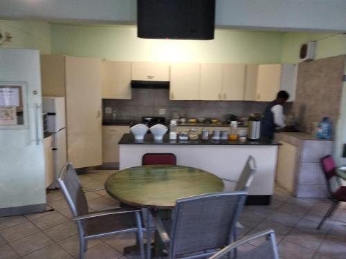 a kitchen with a table and chairs and a person in the kitchen at Brackendene Lodge in Gaborone
