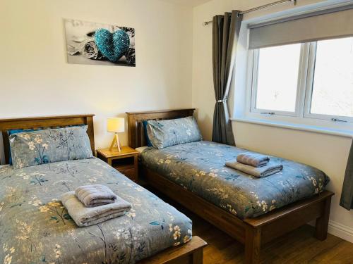 a bedroom with two beds and a window at Thistle Cottage in Fort William