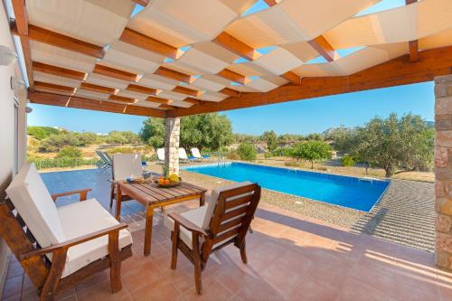 a patio with a table and chairs and a swimming pool at Olive Private Villa Swimming Pool 5 BDR Kolymbia Rhodes in Kolimbia