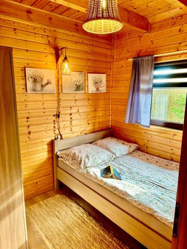 a bedroom with a bed in a wooden cabin at Dolina Bella - domek z balią, basenem, sauną i klimatyzacją w sercu Kaszub in Gołubie