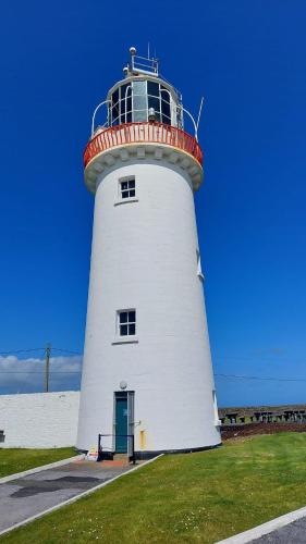 a white lighthouse with a redvisor on top of it at An Sean Teach in Fodry