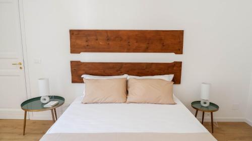 a bedroom with a white bed with two tables at Castellano suites in Castellammare del Golfo