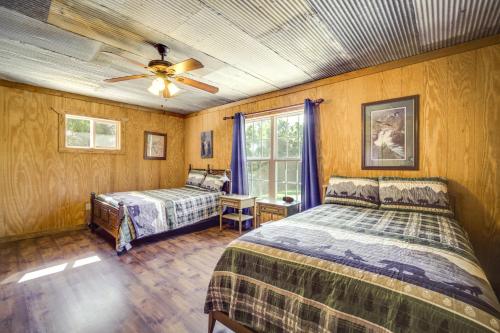 Heflin的住宿－River Bend Lodge Heflin Home in the Woods!，一间卧室配有两张床和吊扇