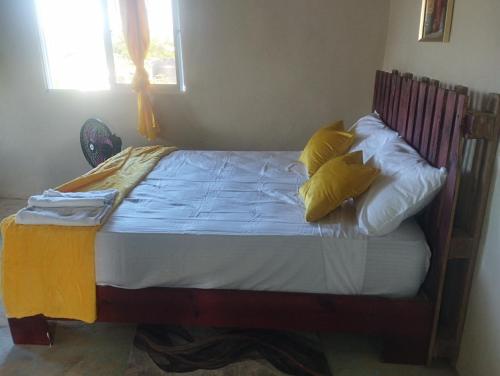 1 dormitorio con 1 cama con almohadas amarillas y blancas en Cabañas Raysa y Alejandro Pasion #3, en Las Galeras