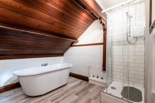 龐蒂浦的住宿－Madison House - Converted Church 5 Bed Pontypool，浴室配有白色浴缸和淋浴。