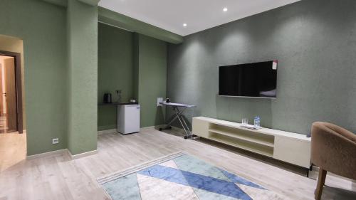 Calipso Dushanbe Hotel في دوسهانبي: غرفة معيشة مع جدران خضراء وتلفزيون بشاشة مسطحة