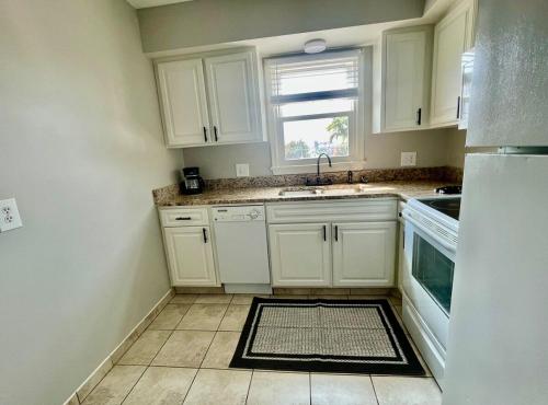 a kitchen with white cabinets and a sink and a window at Cathedra 3l-Charming Apartment walk to UNMC in Omaha