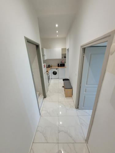 Il comprend une cuisine avec des murs blancs et un grand carrelage. dans l'établissement 2 pièces promenade des anglais, à Nice