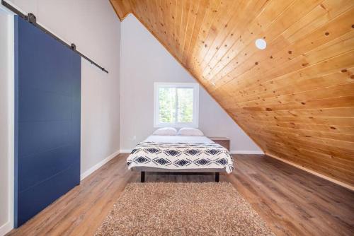 Riverside Retreat: Maazah Cottage في Fort Coulonge: غرفة نوم بسرير وسقف خشبي