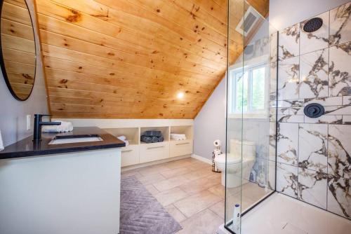 een badkamer met een houten plafond en een douche bij Riverside Retreat: Maazah Cottage in Fort Coulonge