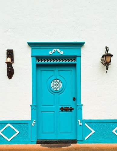 a blue door in front of a white building at Villa Linda ApartaHotel in Jericó