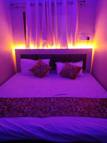 सुभद्रा guest house في Ayodhya: غرفة نوم أرجوانية مع سرير مع أضواء أرجوانية