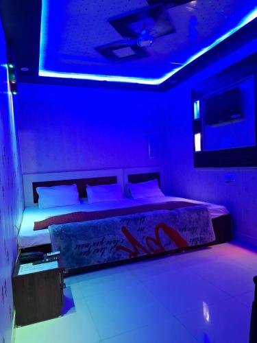 सुभद्रा guest house في Ayodhya: غرفة بها سرير مع أضواء زرقاء