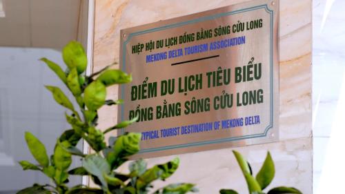 a sign on the side of a wall with a plant at SÀI GÒN - BẠC LIÊU Hotel in Bạc Liêu