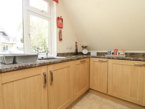 a kitchen with wooden cabinets and a sink and a window at Honeycombe Lodge in Callington