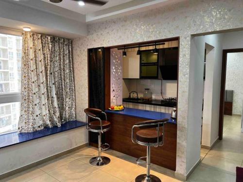 a kitchen with two bar stools in front of a window at Cozy 1 BHK apartment in Bhartiya City in Yelahanka