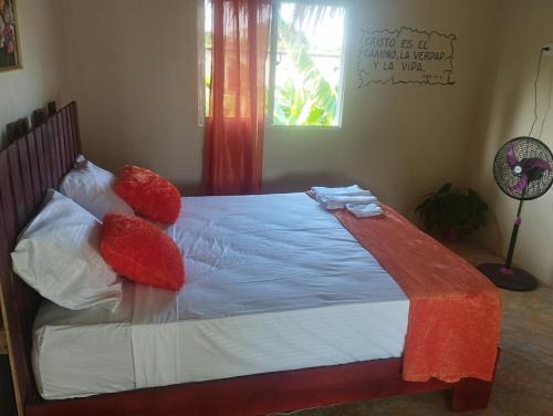 1 cama con almohadas rojas en el dormitorio en Cabañas Raysa y Alejandro Comprension #4, en Las Galeras