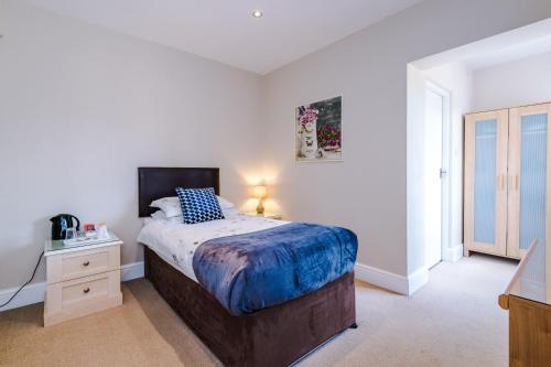 a bedroom with a bed and a dresser with a night stand at Holcombe Guest House in Barnetby le Wold