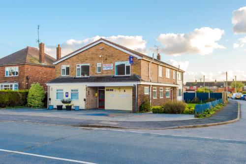 a brick building with a garage on a street at Holcombe Guest House in Barnetby le Wold