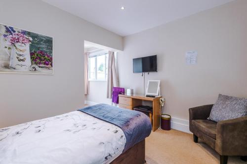 a bedroom with a bed and a chair and a desk at Holcombe Guest House in Barnetby le Wold