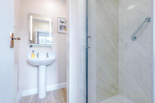 a white bathroom with a sink and a shower at Holcombe Guest House in Barnetby le Wold
