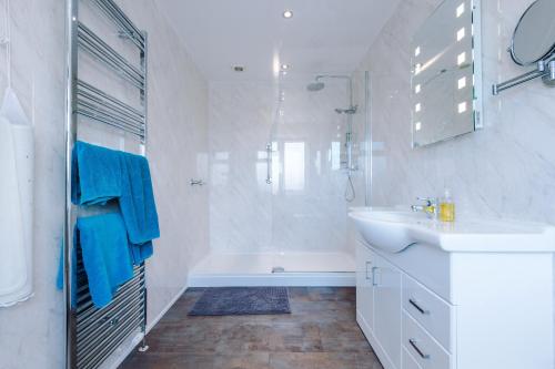 a white bathroom with a sink and a tub at Holcombe Guest House in Barnetby le Wold