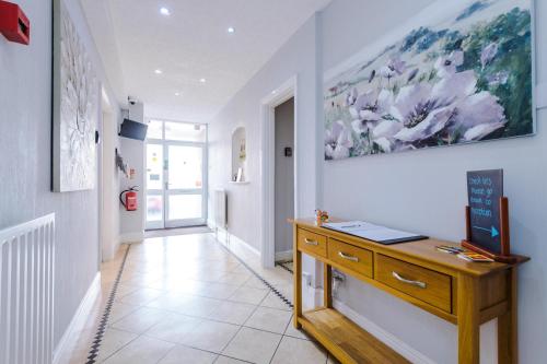 a hallway with a desk and a painting on the wall at Holcombe Guest House in Barnetby le Wold