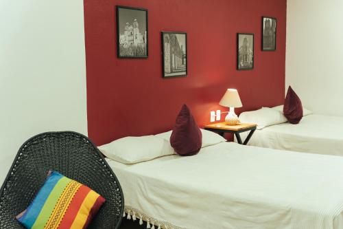 Duas camas num quarto com paredes vermelhas e uma cadeira em Casa Don José: GRANADAS em Oaxaca City
