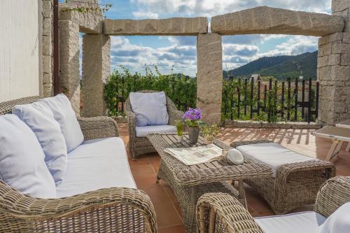 a patio with wicker chairs and tables with a view at BGItalianVacation - Ville Li Conchi in Castiadas