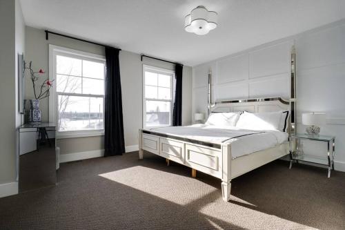 a bedroom with a white bed and two windows at Executive Condo (boutique hotel-like) in Ottawa